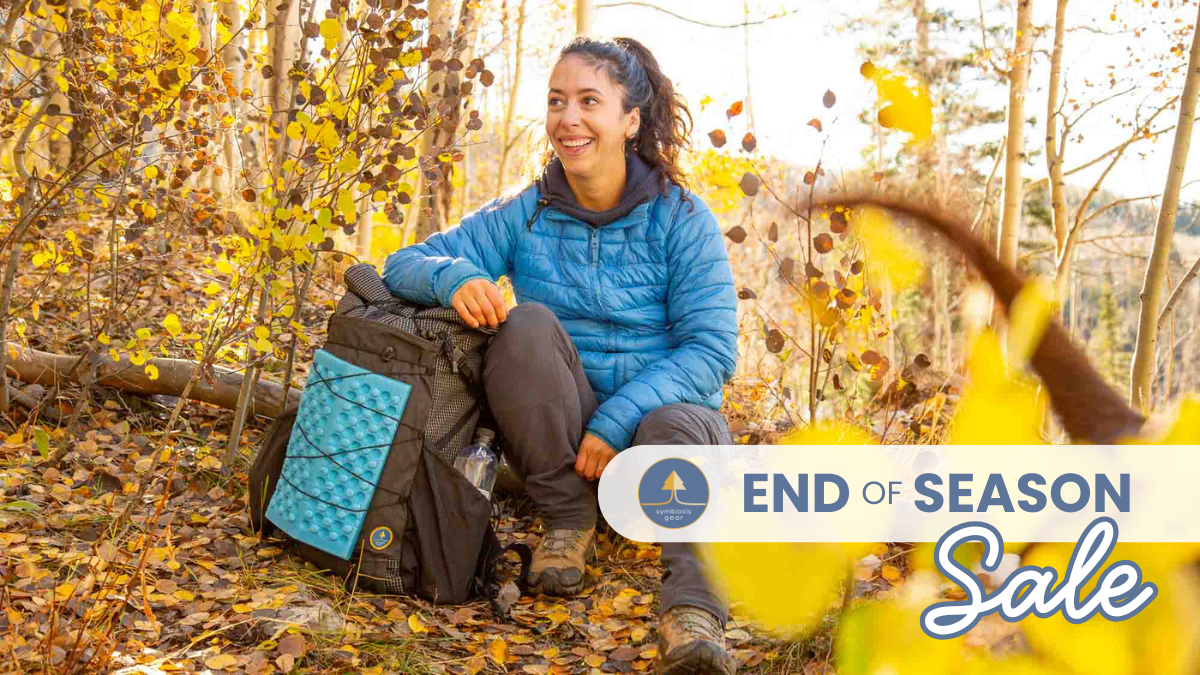 Woman sitting in a forest with a backpack, surrounded by autumn leaves, with 'End of Season Sale' text overlay.
