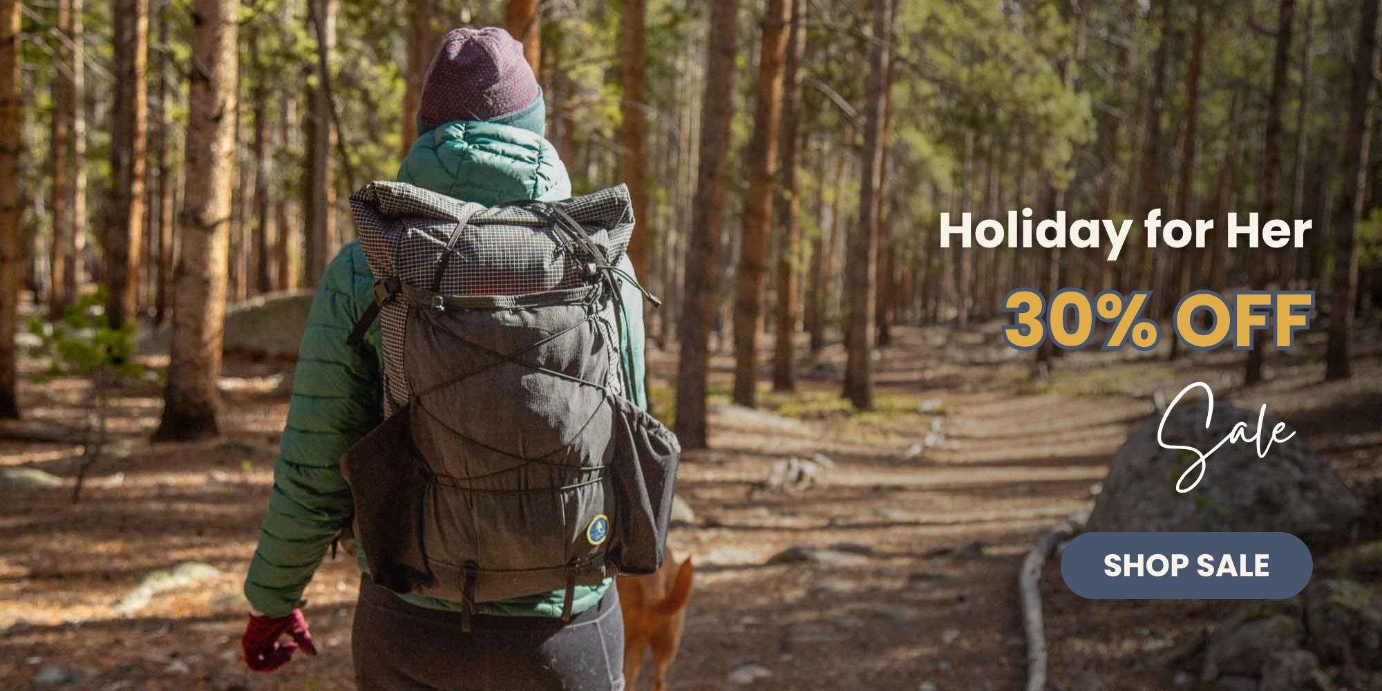 Person with a backpack walking through a forest with promotional text for a 'Holiday for Her' sale.